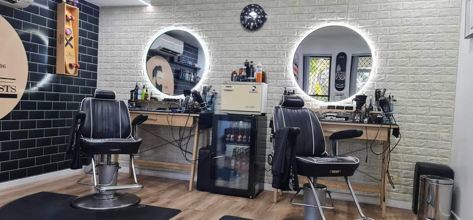 Barber chairs, backlit round mirrors and grooming stations inside Mojo's Stylist barbershop